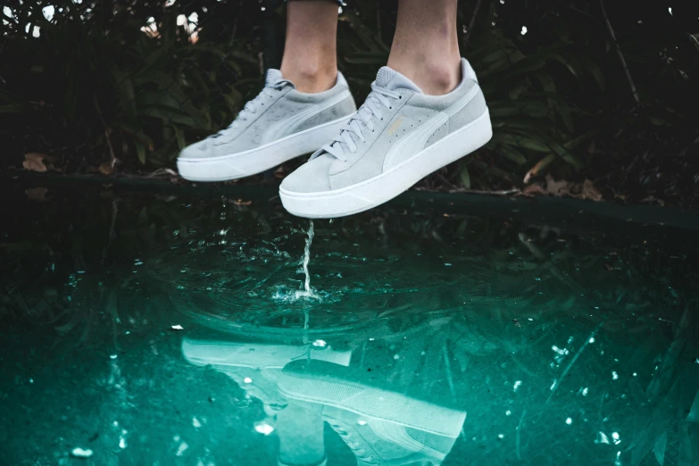 a pair of feet hanging above a pool of water