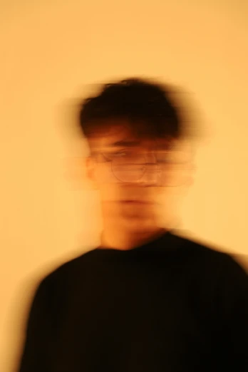 a blurry image of a man with glasses on and his eyes shut