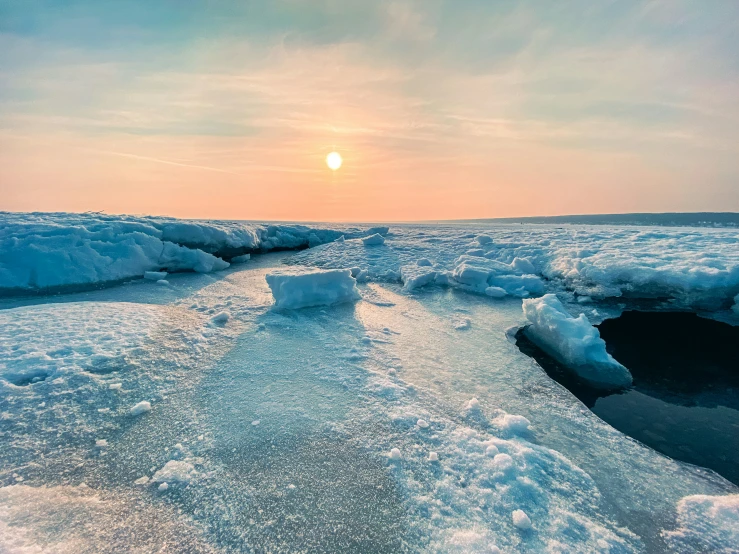 sun rising on the horizon above the snow and ice