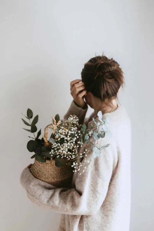 a woman is holding a basket filled with flowers