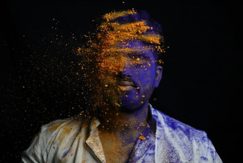 a man in white shirt posing with his face sprinkled with yellow powder