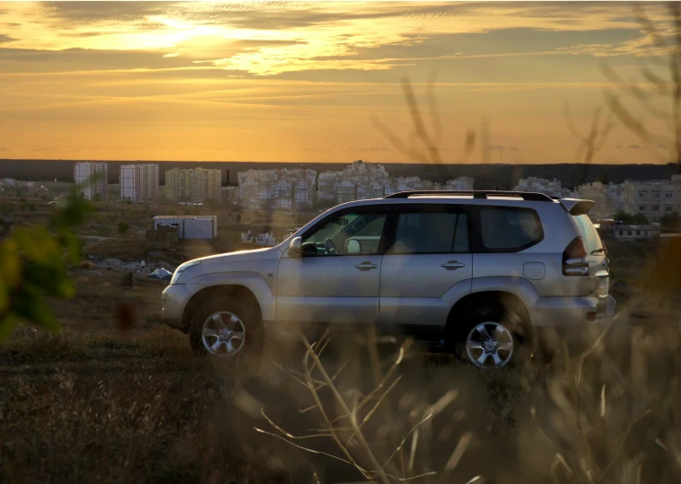 a white suv in field next to a city