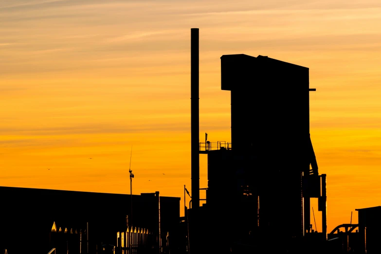 a tower like building is silhouetted against the bright orange sky