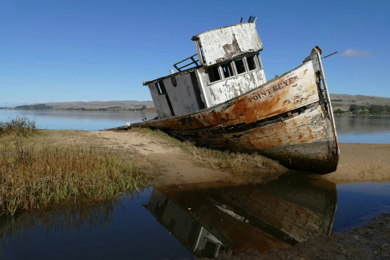 an old abandoned boat sitting on the shore