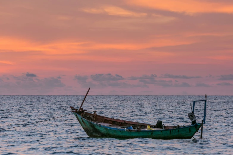 an empty boat floating on the water at sunset