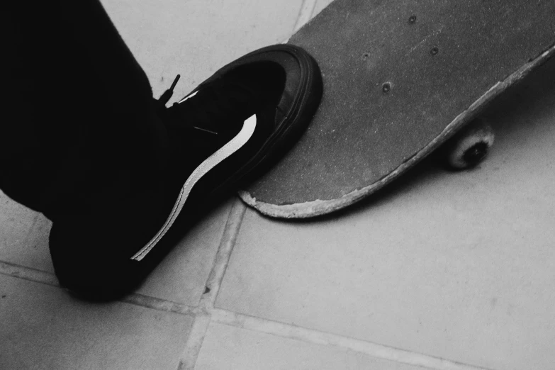 person in black and white sneakers standing next to skateboard