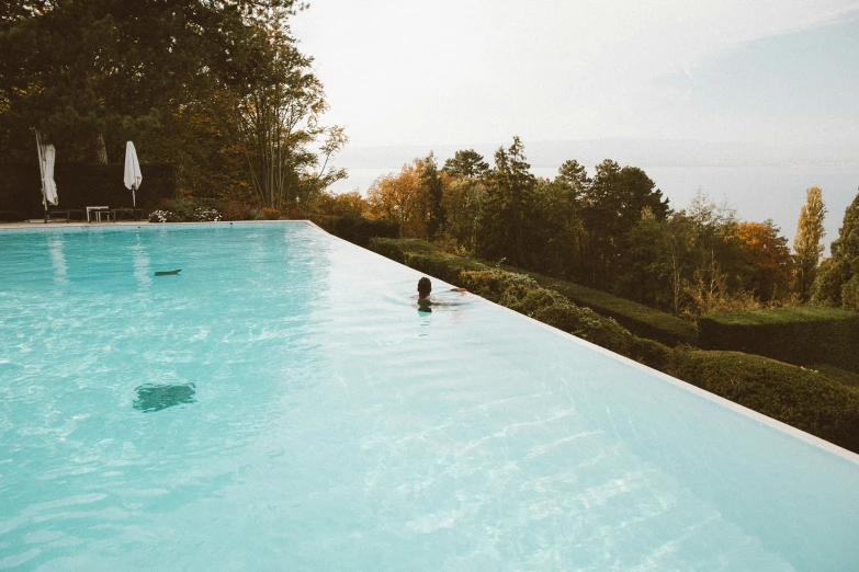 a woman stands by a large blue pool