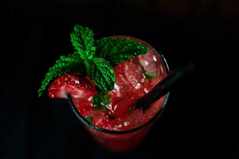 two strawberries and mint sitting on a black table