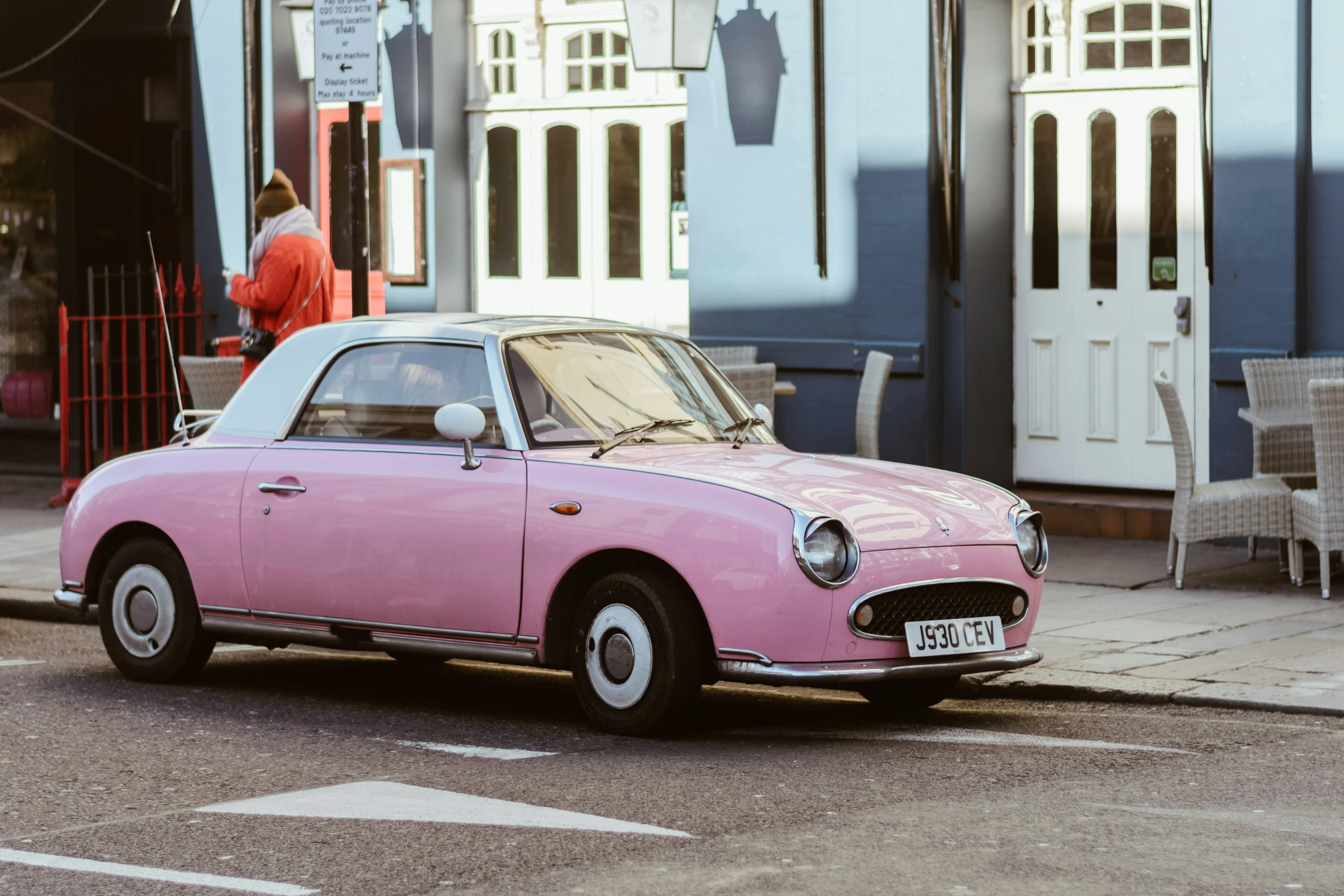 an old pink car parked in front of a blue house