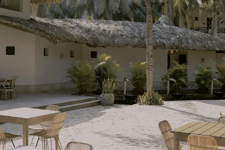 a courtyard area with tables and chairs and a straw roof