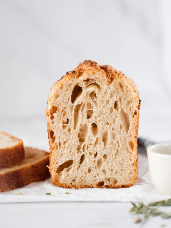 a loaf of bread that is sliced in half and next to a small cup