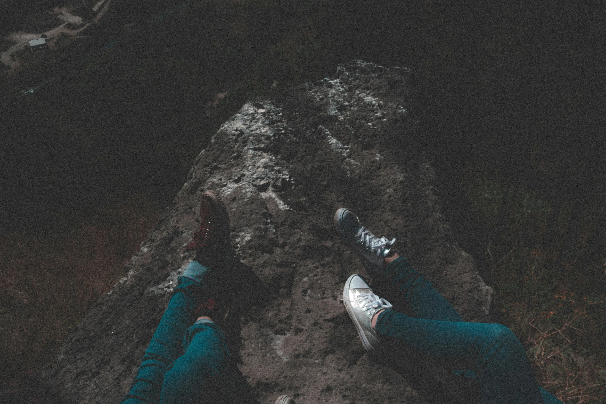 two people laying on top of rocks and a sky background