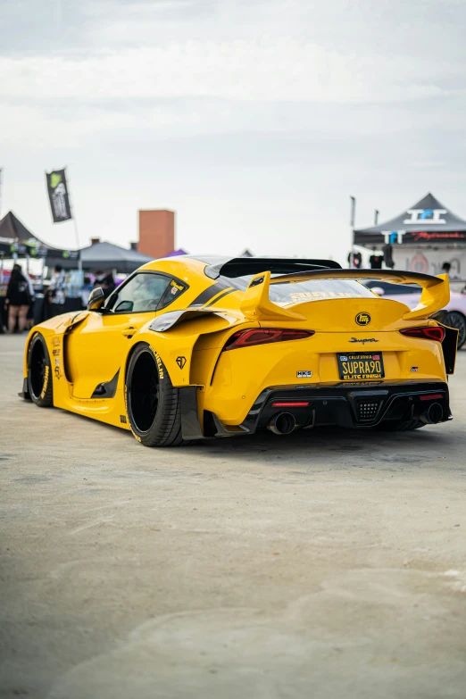 the rear end of a yellow sports car parked on a lot