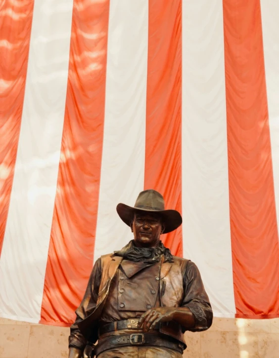 a statue of a cowboy wearing a hat with a bag and belt around his waist