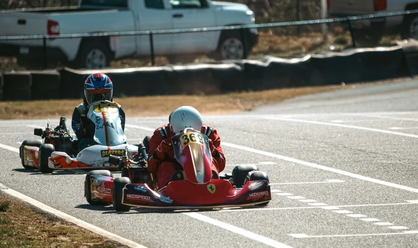 two people riding go kart racing down a road