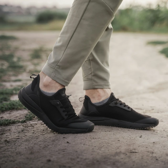a man's foot in black shoes walking on a sidewalk