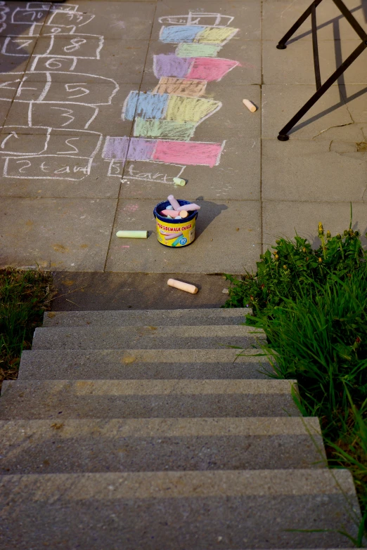 chalk markers are on the concrete next to stairs