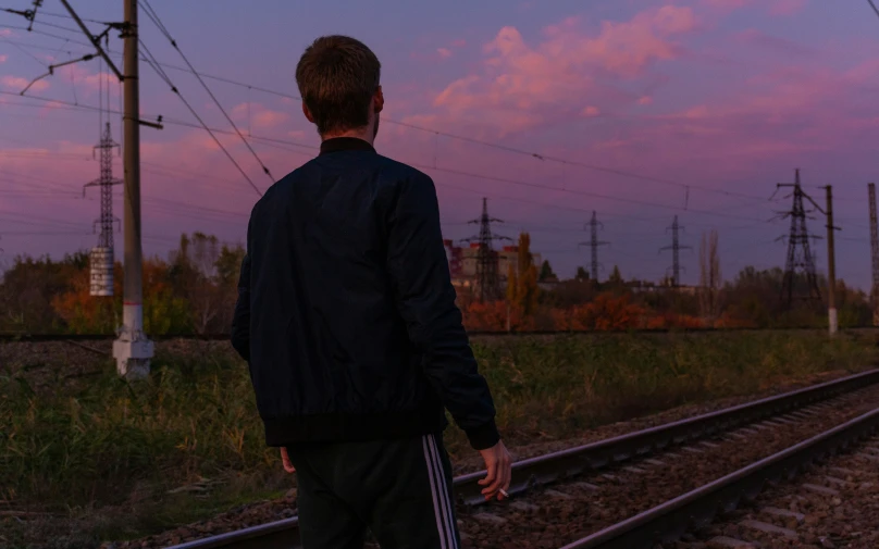 a man walking across tracks toward the sky