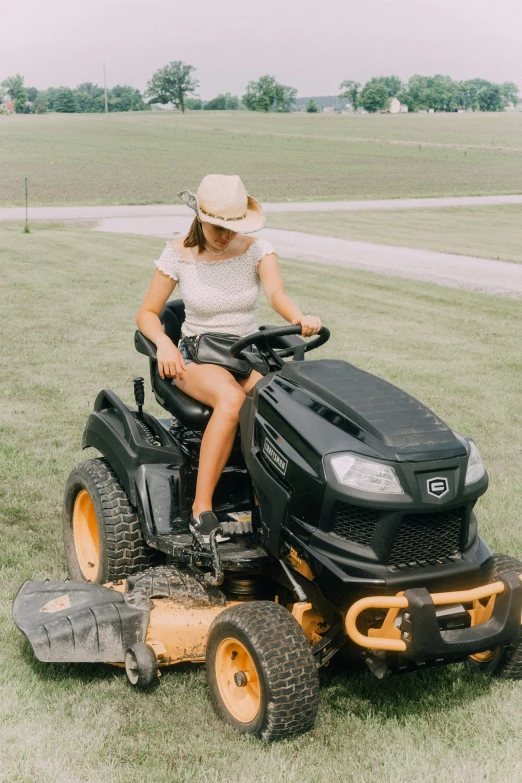 a woman sitting on a black tractor in a field