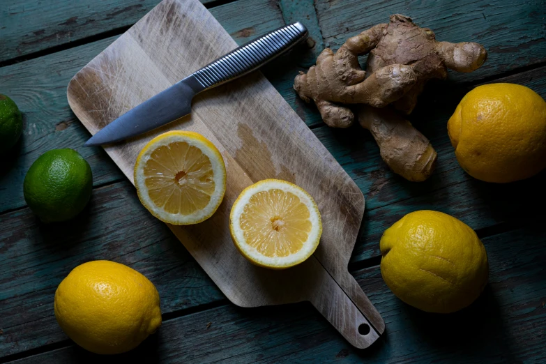 some cut up lemons sitting on a  board and a ginger root