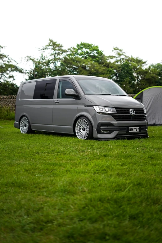 the van is parked in the grass with the tent behind it