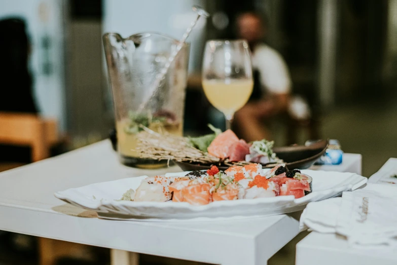 a plate of sushi with sauce on it and another glass