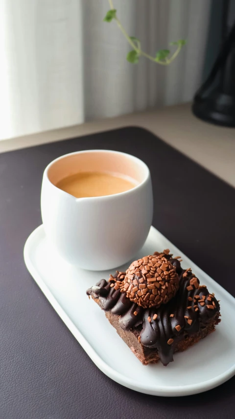 a square plate with a pastry on it and coffee in the background