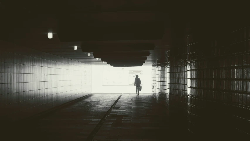 a silhouette of a person standing in a dark tunnel