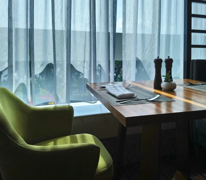 a window next to two green chairs sitting in front of a table