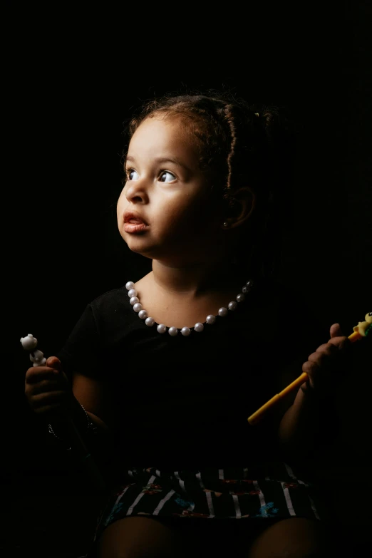 a girl holding a toothbrush up with a dark background