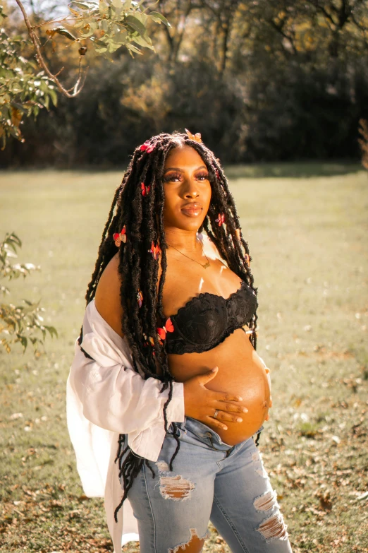 a beautiful black pregnant woman poses in a field