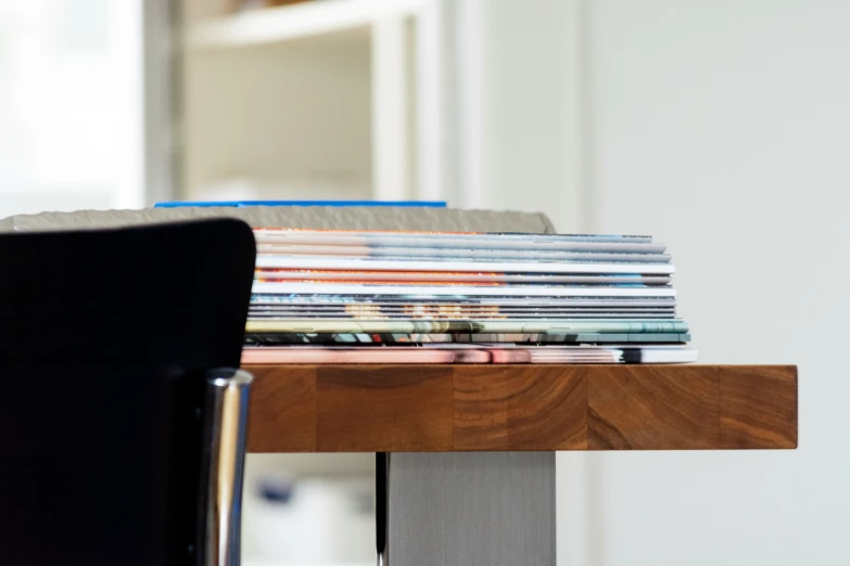 stacks of magazines sit on a desk in front of a laptop