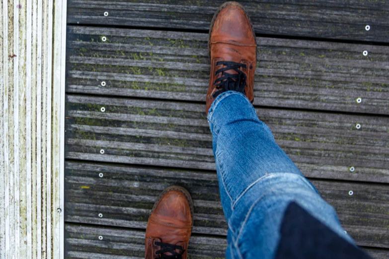 a person's shoes and jeans on the ground with their legs crossed
