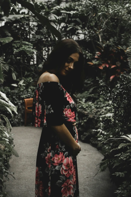 a woman is looking down as she stands between plants