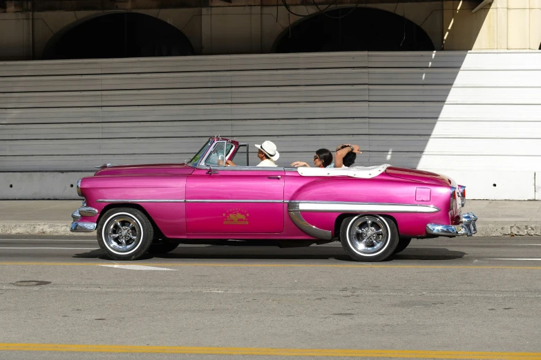 pink convertible car with people in back seat