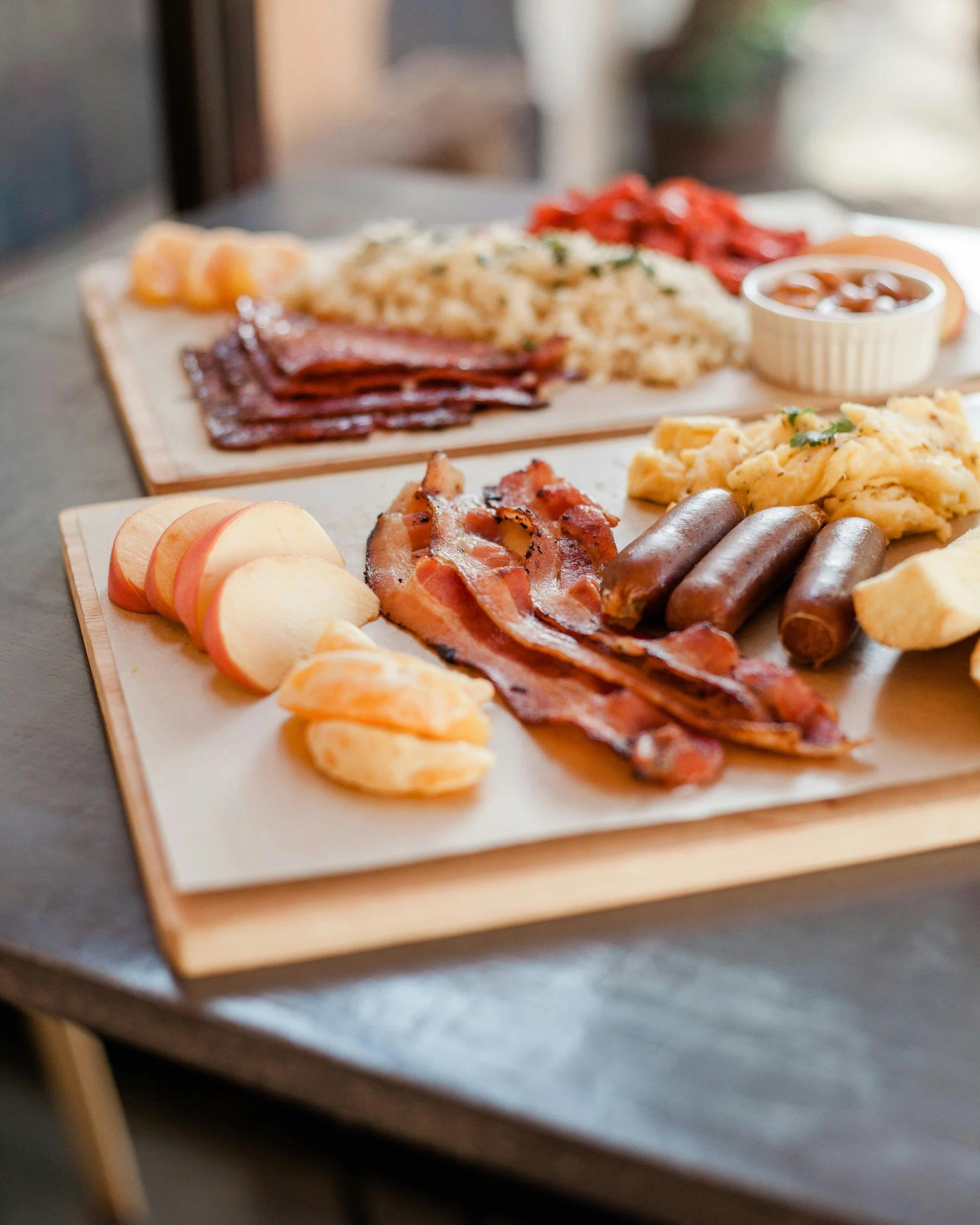 an array of different bacons, cheeses and other foods sit on two wooden plates