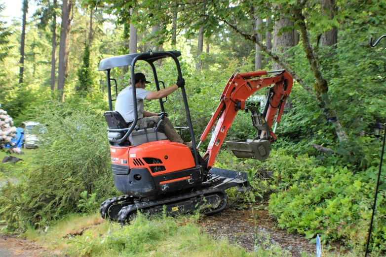 an orange mini excavater is being used on the side of a road