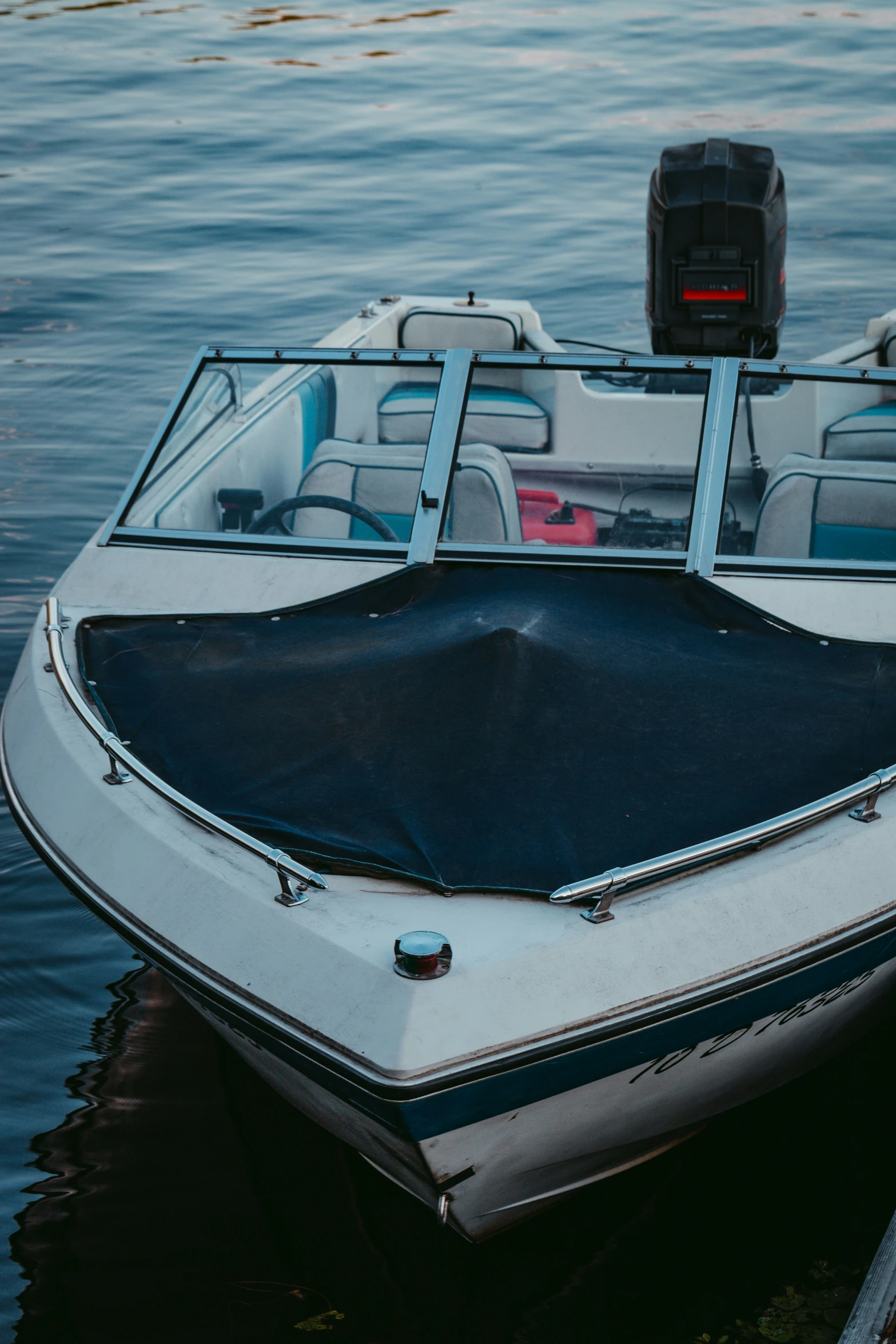 a white boat floating in the water with it's front door open