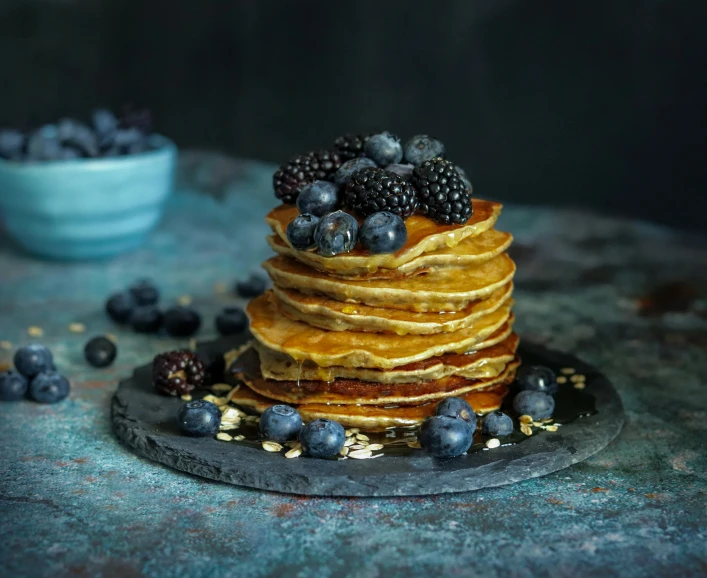 the stack of pancakes with blueberries and other toppings are topped with blackberries