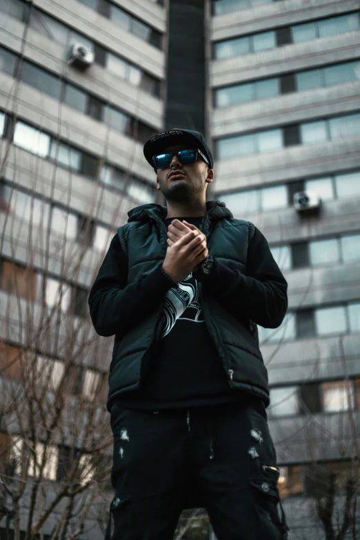 man standing outside wearing glasses in front of building