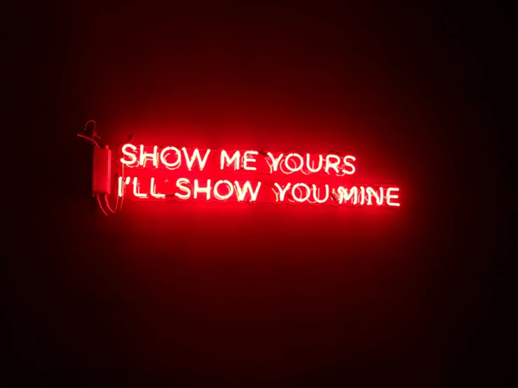 the neon sign is written in red, on a dark background
