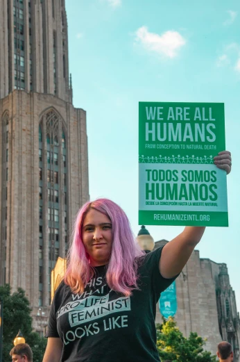 a women with pink hair holding a sign