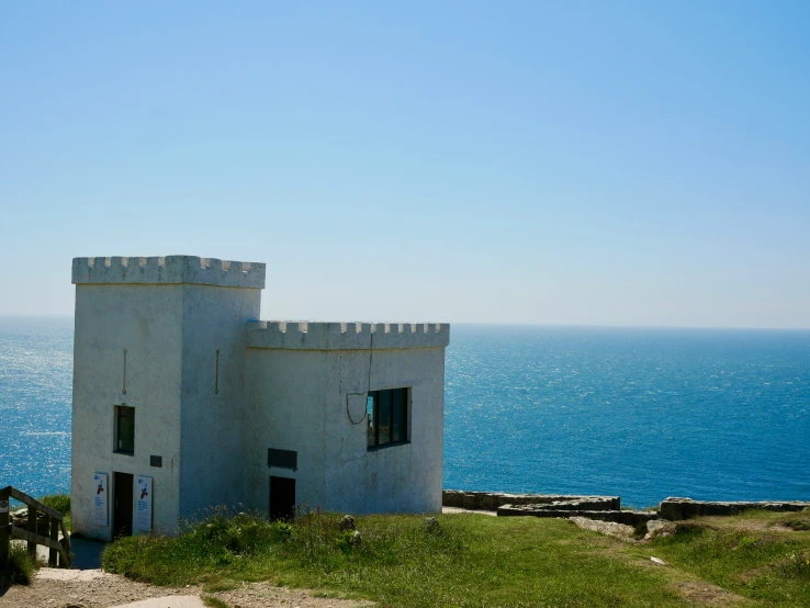 a small castle with a gate overlooking a body of water