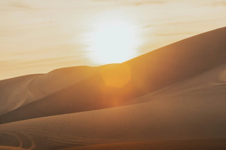 the sun shining down on a desert with sand dunes