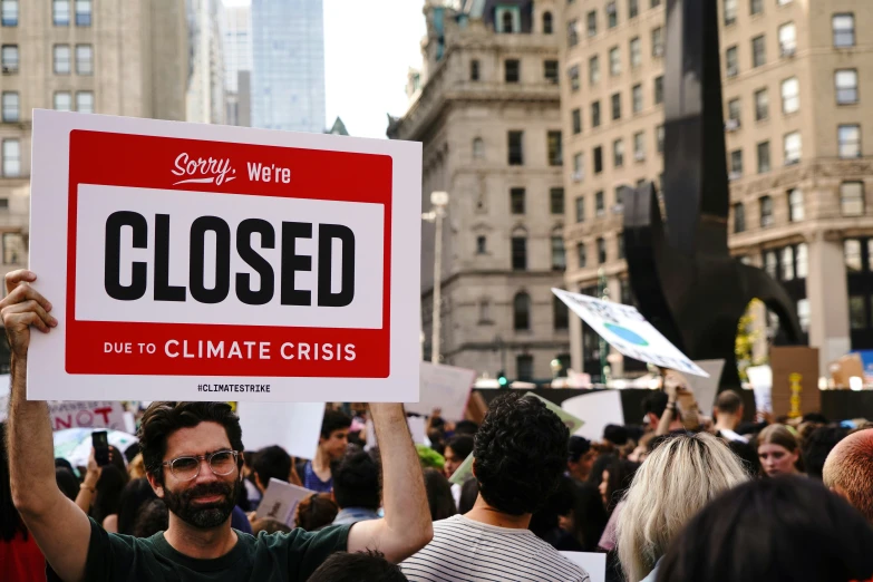 man holding up a closed sign while standing next to others