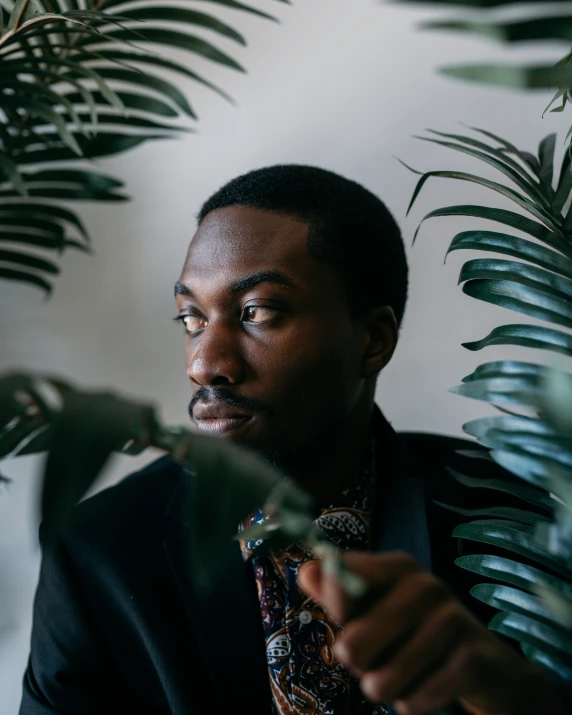 a man sitting in front of leaves and plants