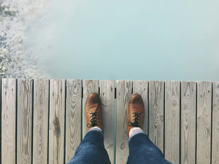 feet on a wooden boardwalk overlooking the water
