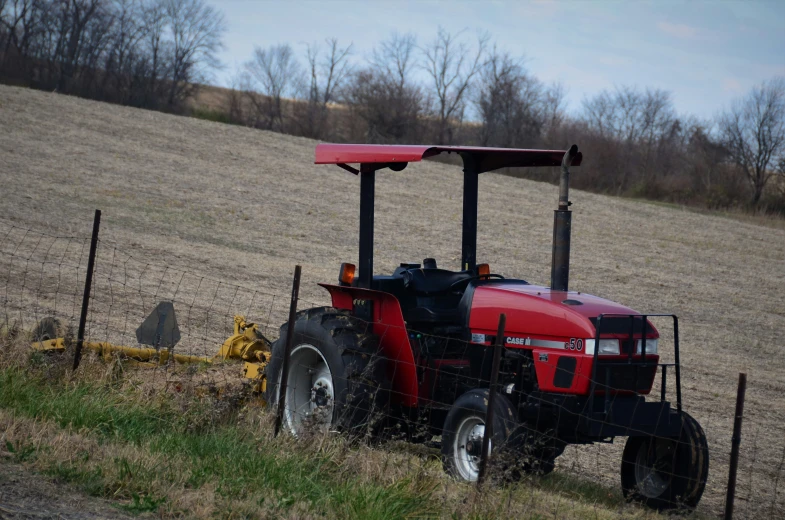 a red tractor sitting in the middle of a field