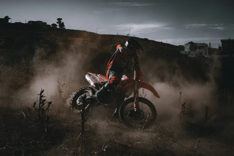 man in full racing gear riding motorcycle through the dust