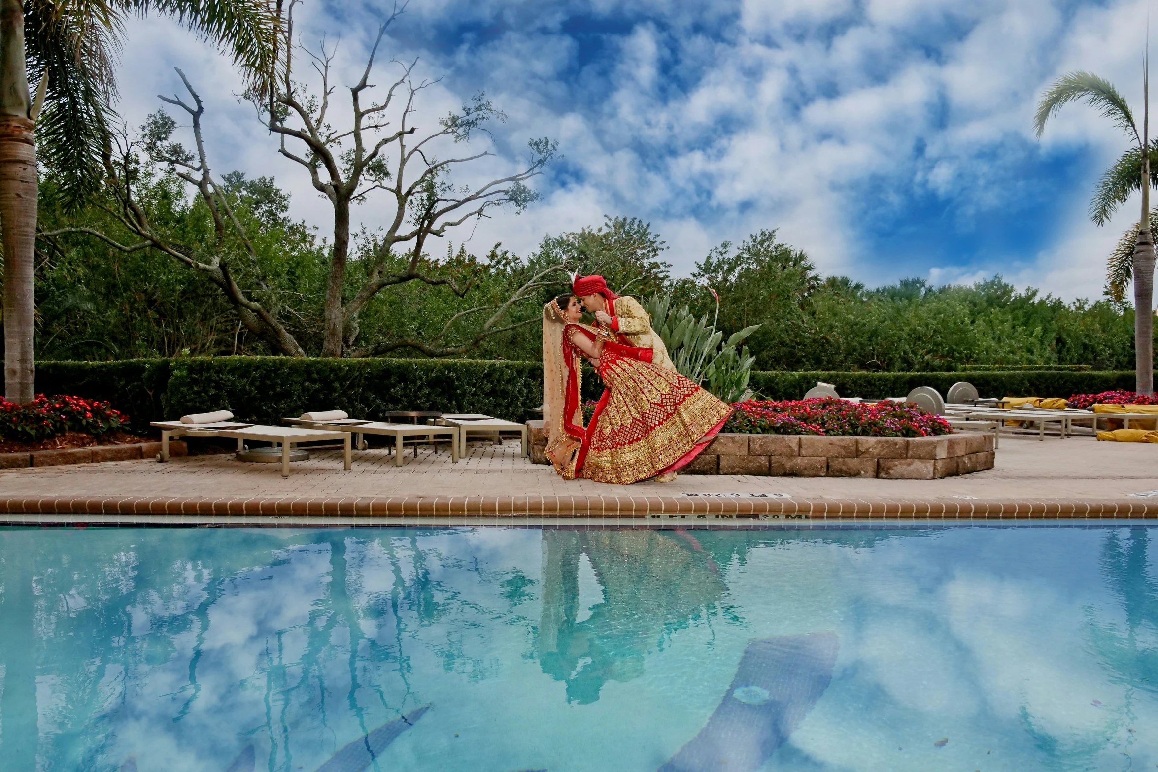 a woman in a bridal gown sitting next to a pool